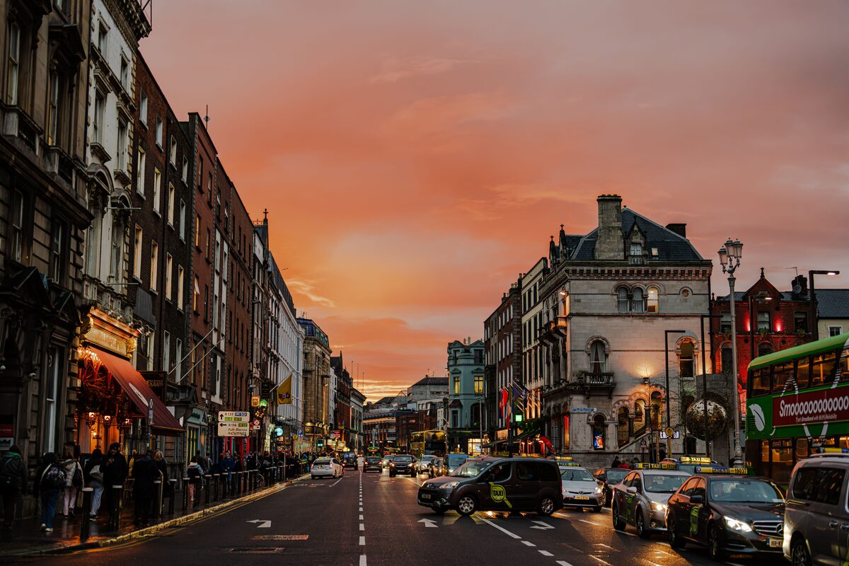 Vibrant city street in Dublin, Ireland during a stunning sunset, showcasing urban life.