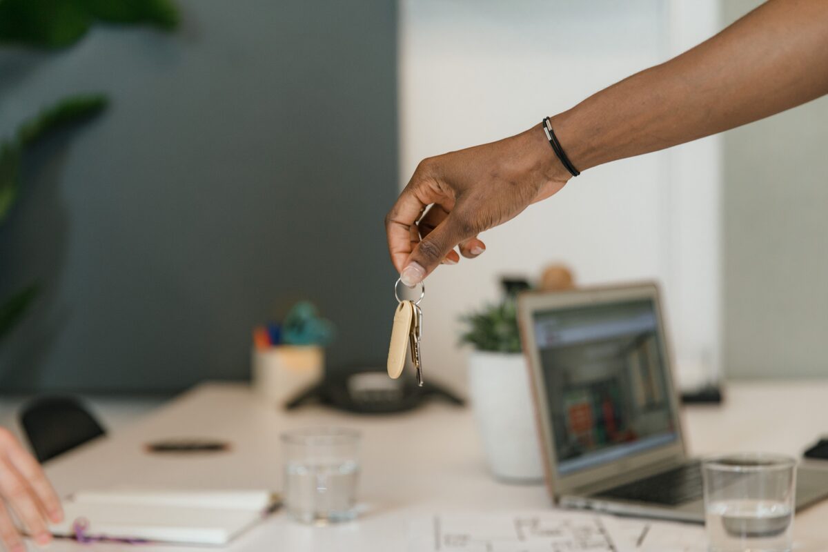 Close-up of a handshake exchanging keys in an office setting.