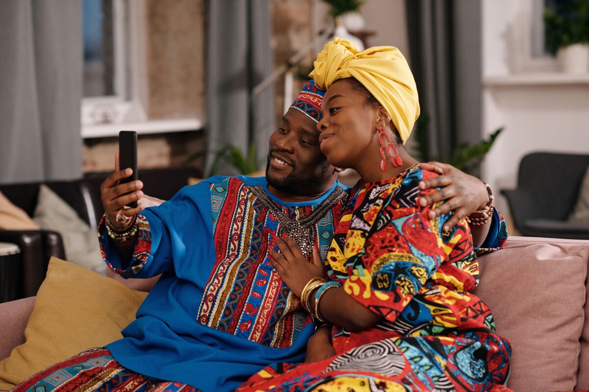 A joyful couple in colorful traditional clothing enjoying a video call indoors.