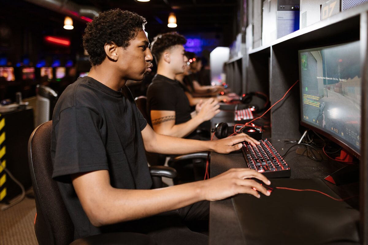 Group of young adults deeply engaged in competitive online gaming at a cyber cafe.