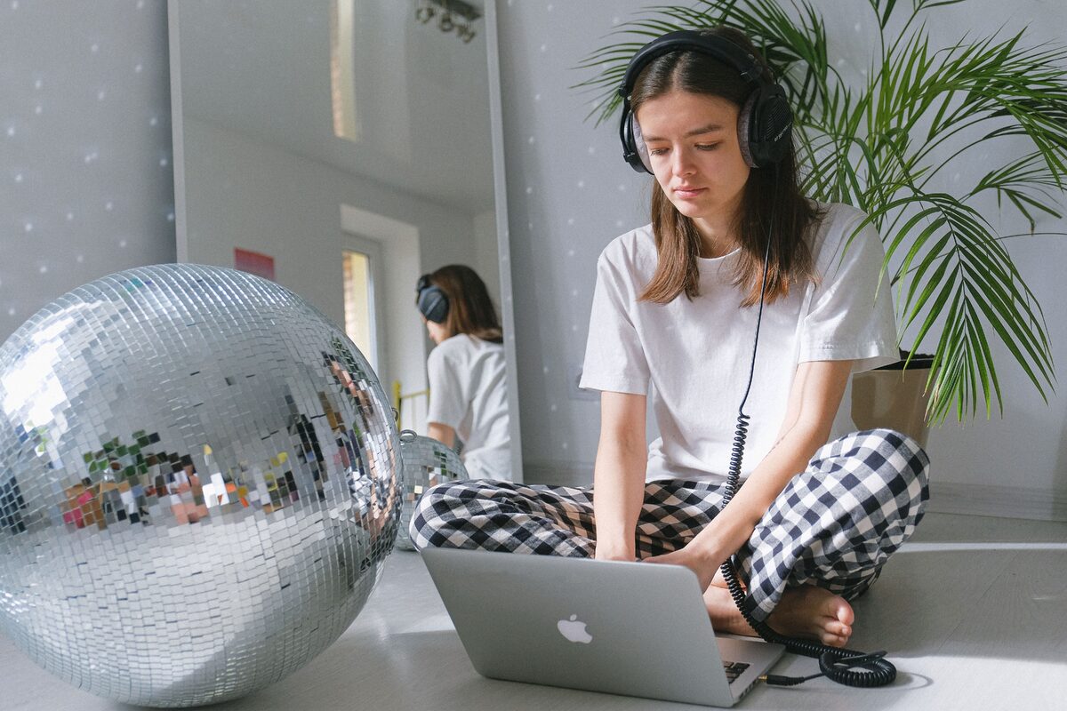 Woman enjoying music while working remotely with a laptop at home.
