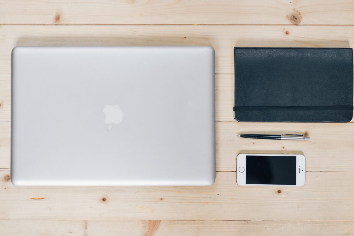 A clean, organized desk featuring a laptop, smartphone, notebook, and pen, ideal for productivity.