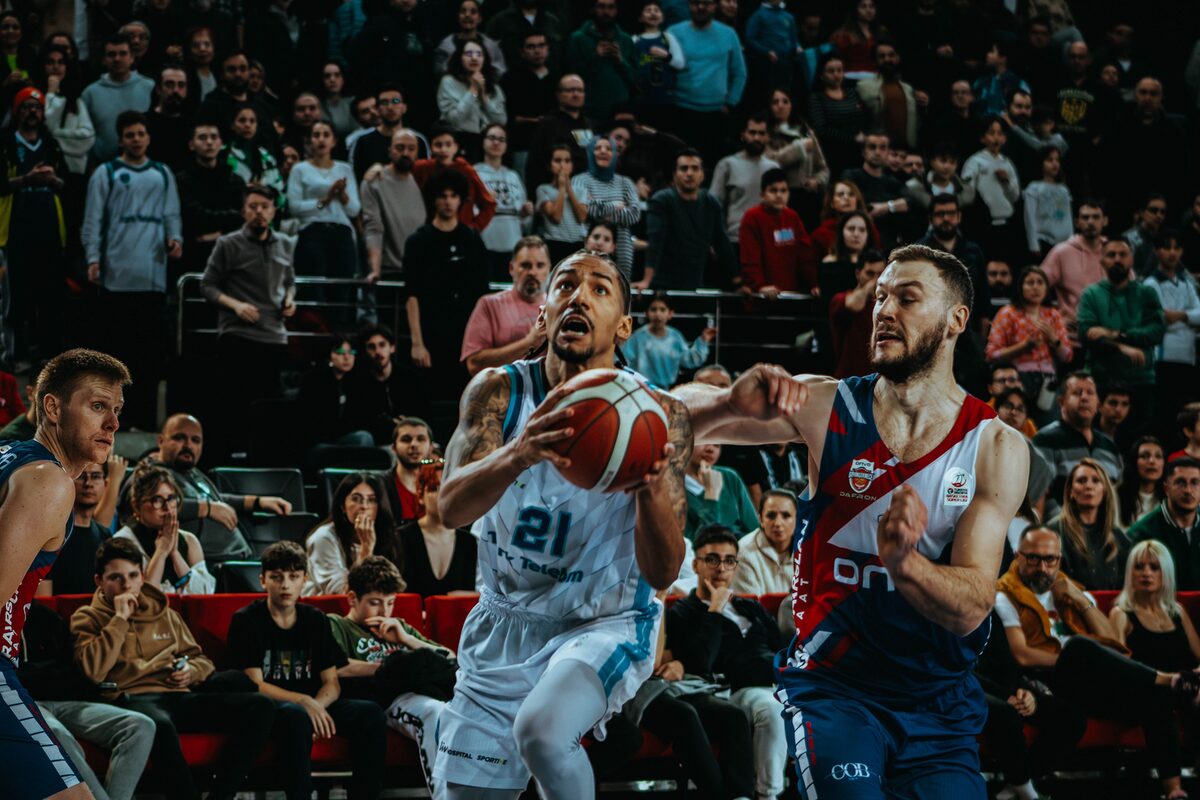 Dynamic action shot from a live basketball game capturing the competition and audience involvement.