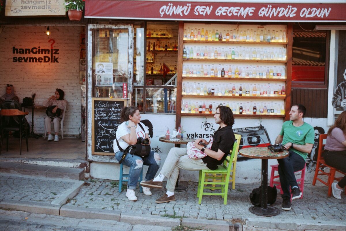People enjoy a relaxed evening sitting outside a cozy urban cafe.