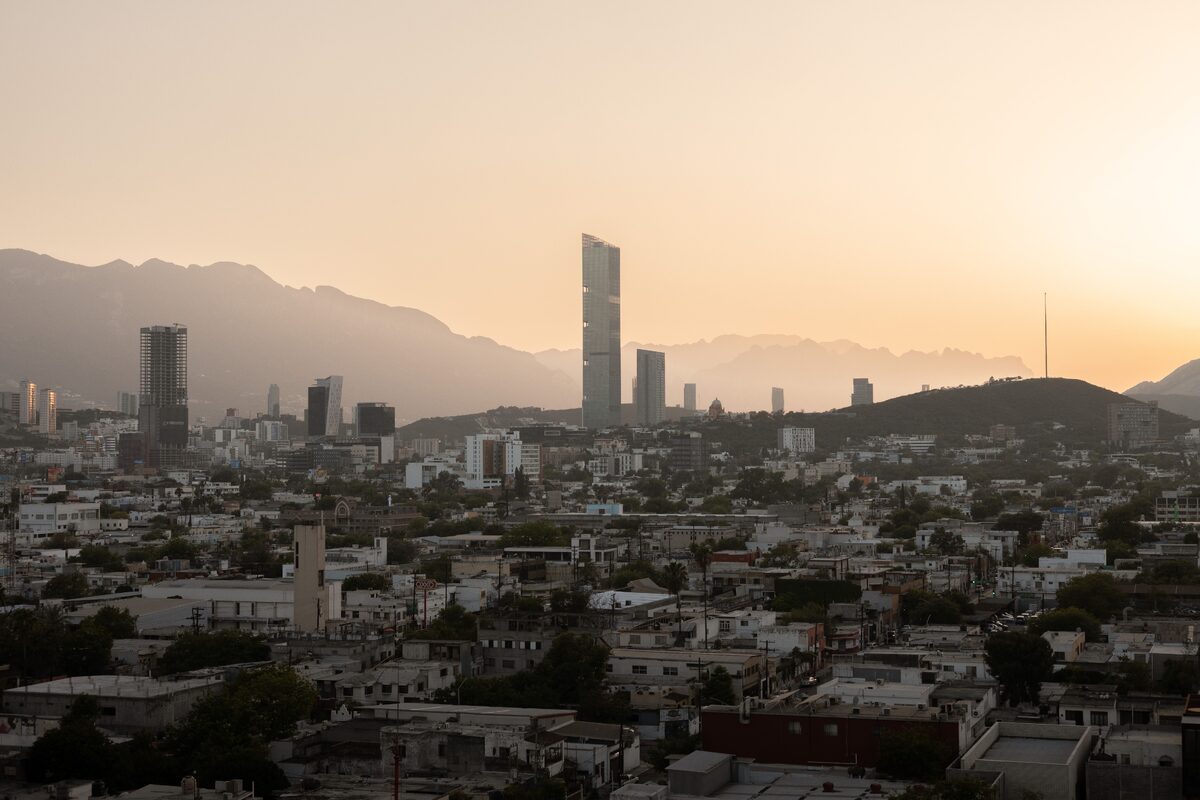 Aerial view of Monterrey's skyline at sunset, featuring modern skyscrapers and mountains.