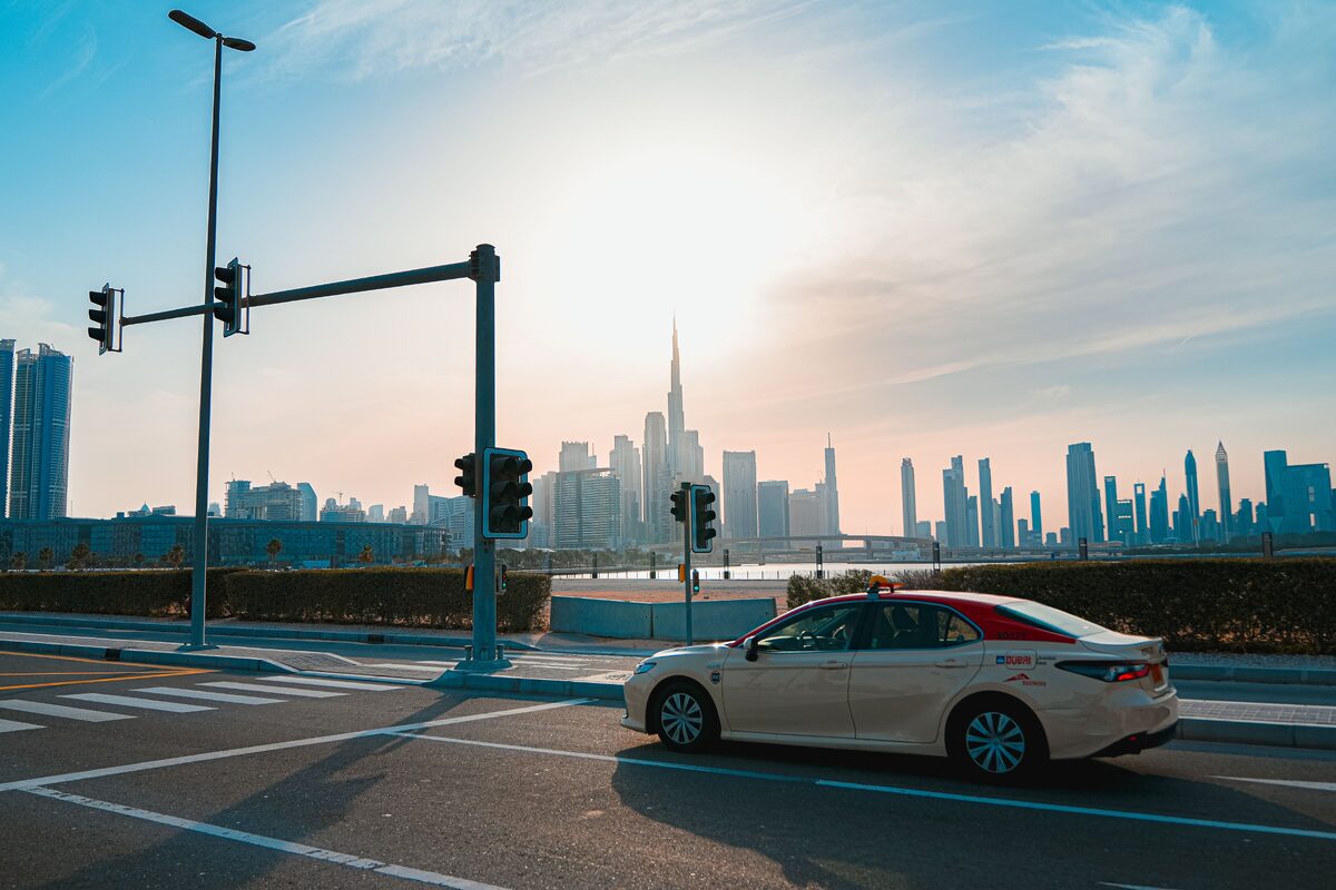 A cityscape photo featuring the iconic Burj Khalifa and a taxi in Dubai during the day.