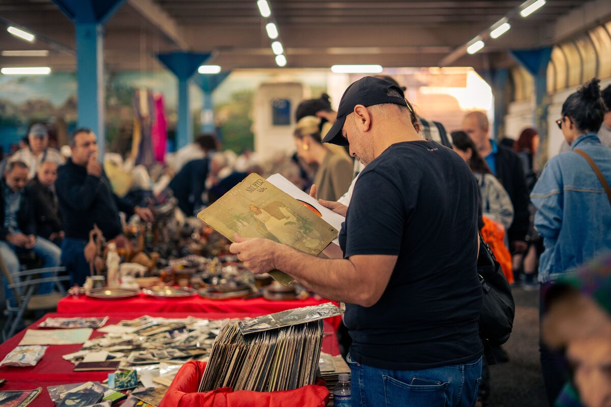 A man browsing vinyl records at a bustling indoor bazaar in İstanbul, Türkiye.