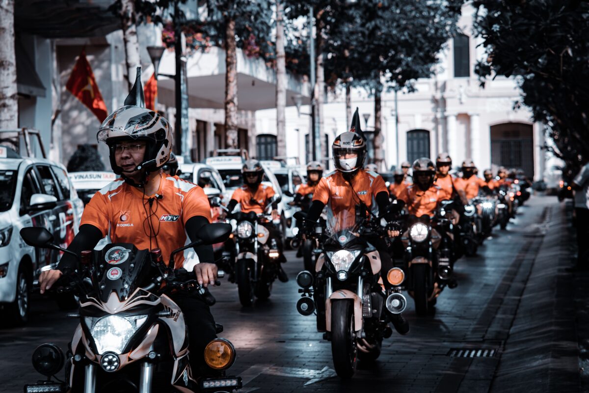 A group of motorcyclists in bright uniforms riding through an urban city street.