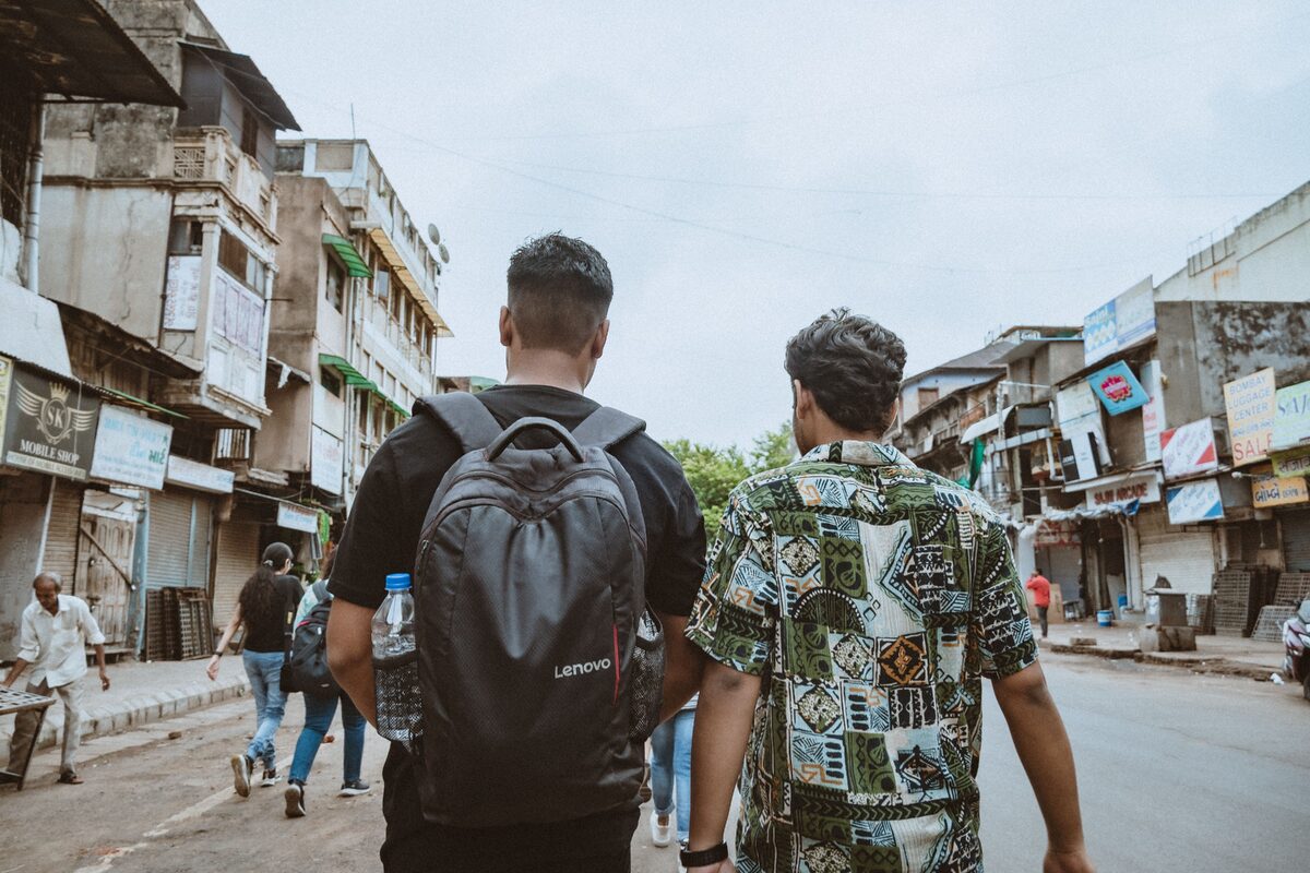 Two men walk through a lively urban street, showcasing diverse culture and city life.