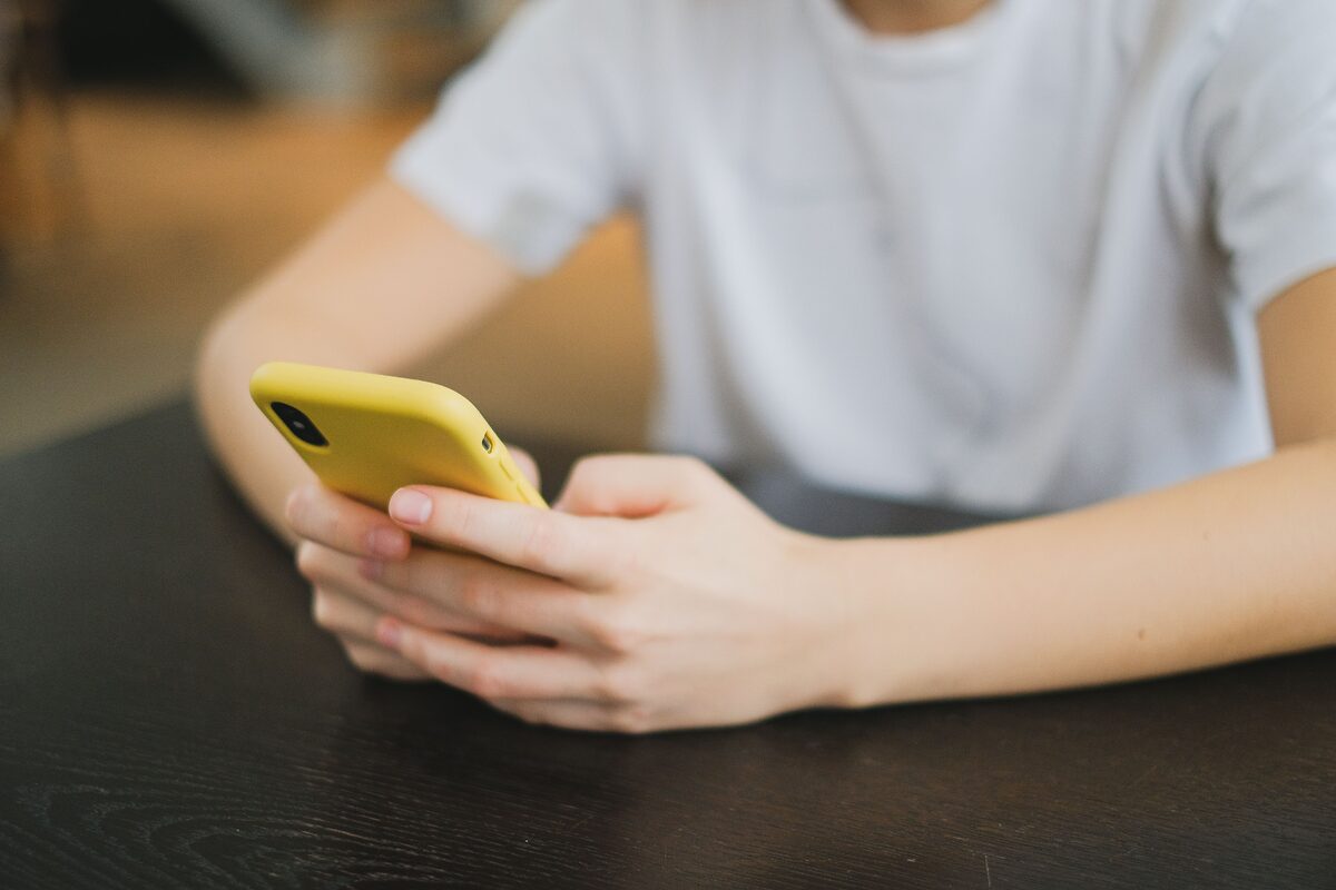 Close-up of person holding a yellow smartphone indoors, focused on the hands and gadget.