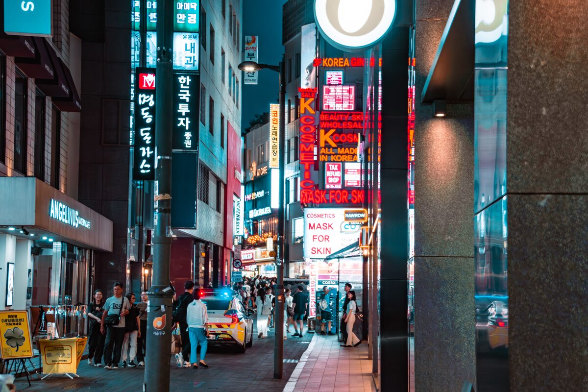 A bustling night scene in Myeongdong, Seoul, showcasing vibrant signs and street activity.