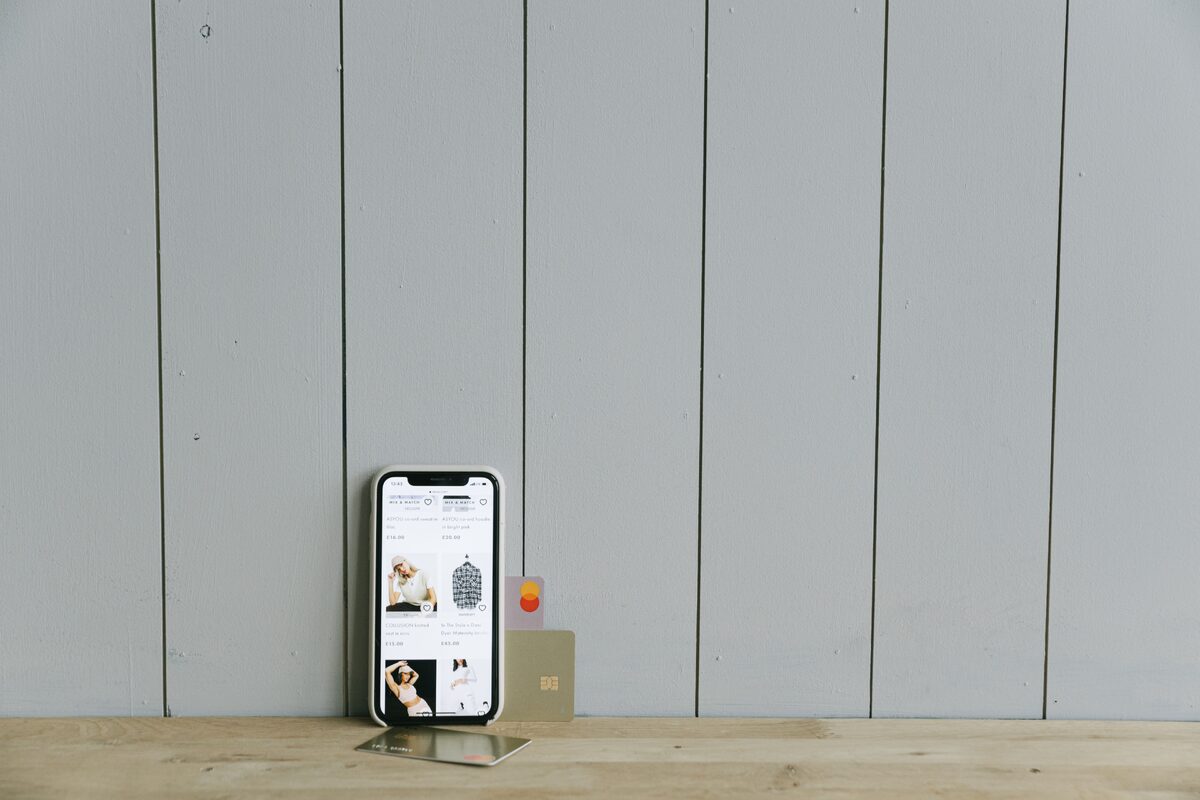 A smartphone displaying an ecommerce site with a credit card, set on a wooden surface, depicting online shopping.