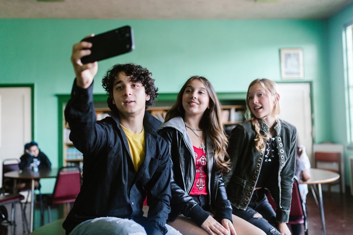 Group of teenagers capturing a fun selfie together indoors, showcasing friendship.