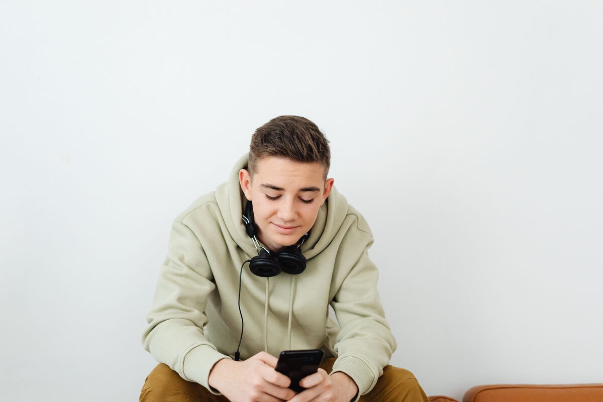 Young person enjoying technology, wearing casual clothes and headphones.