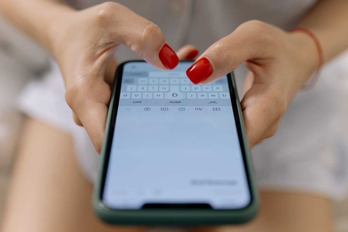 A person holding a smartphone, typing a message with both thumbs