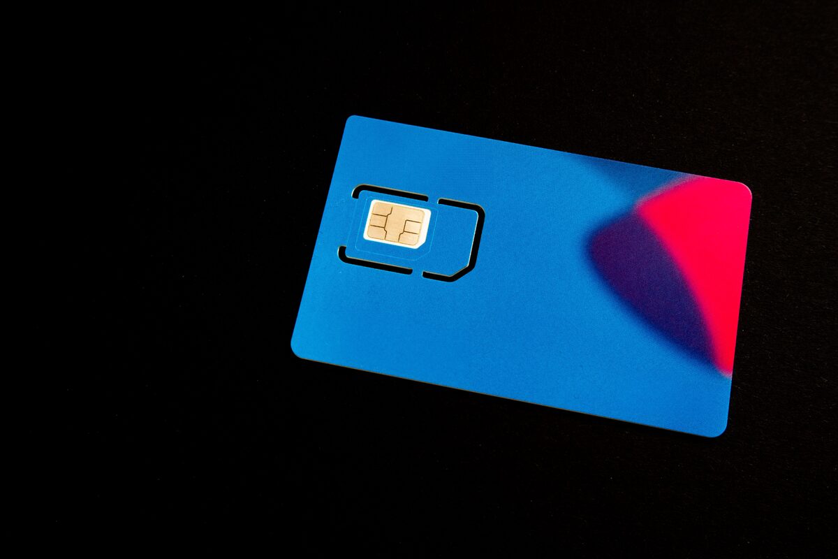 A SIM card lying on a plain background next to a phone tray