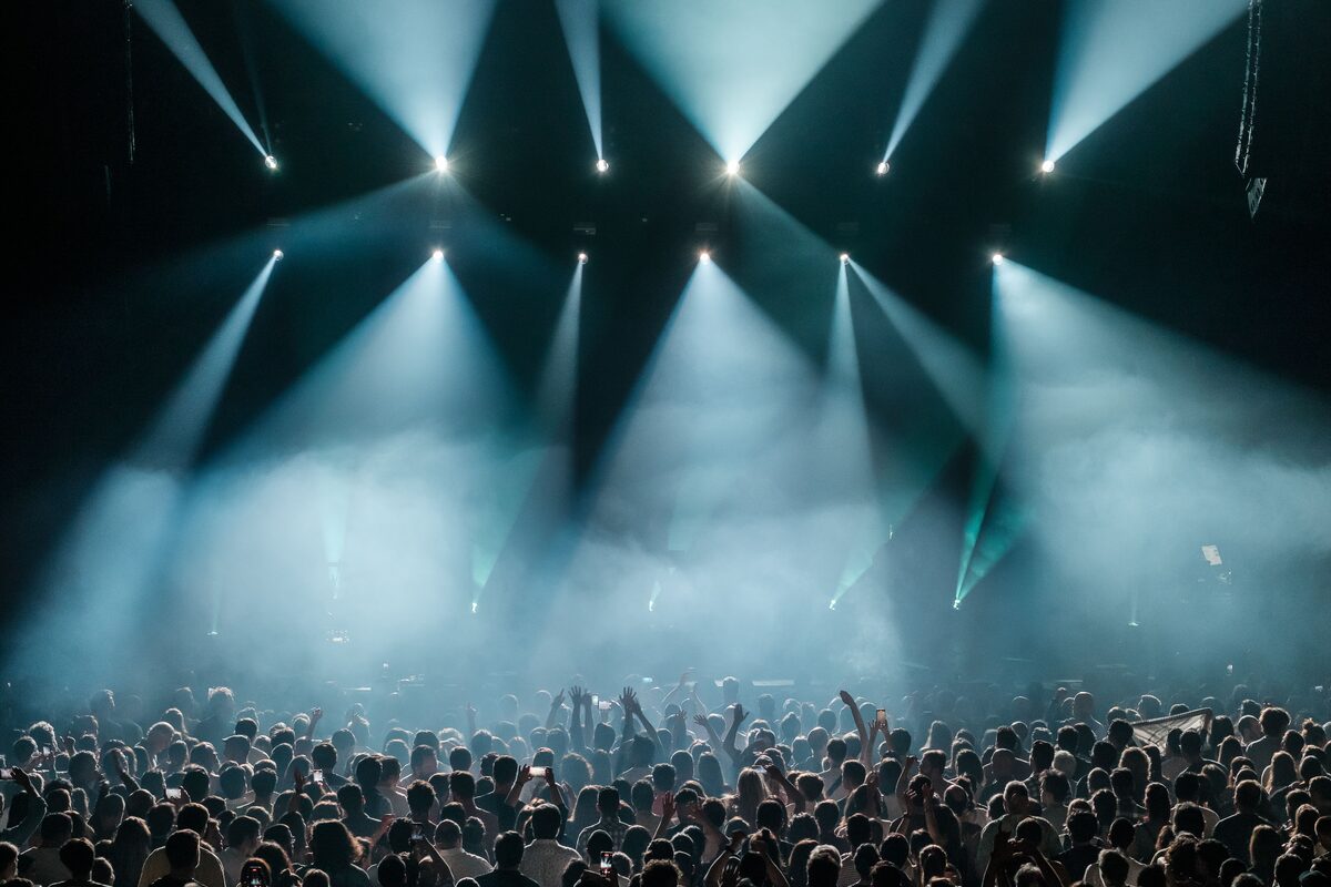 A dynamic concert scene with a large crowd enjoying vibrant stage lighting and a lively atmosphere.