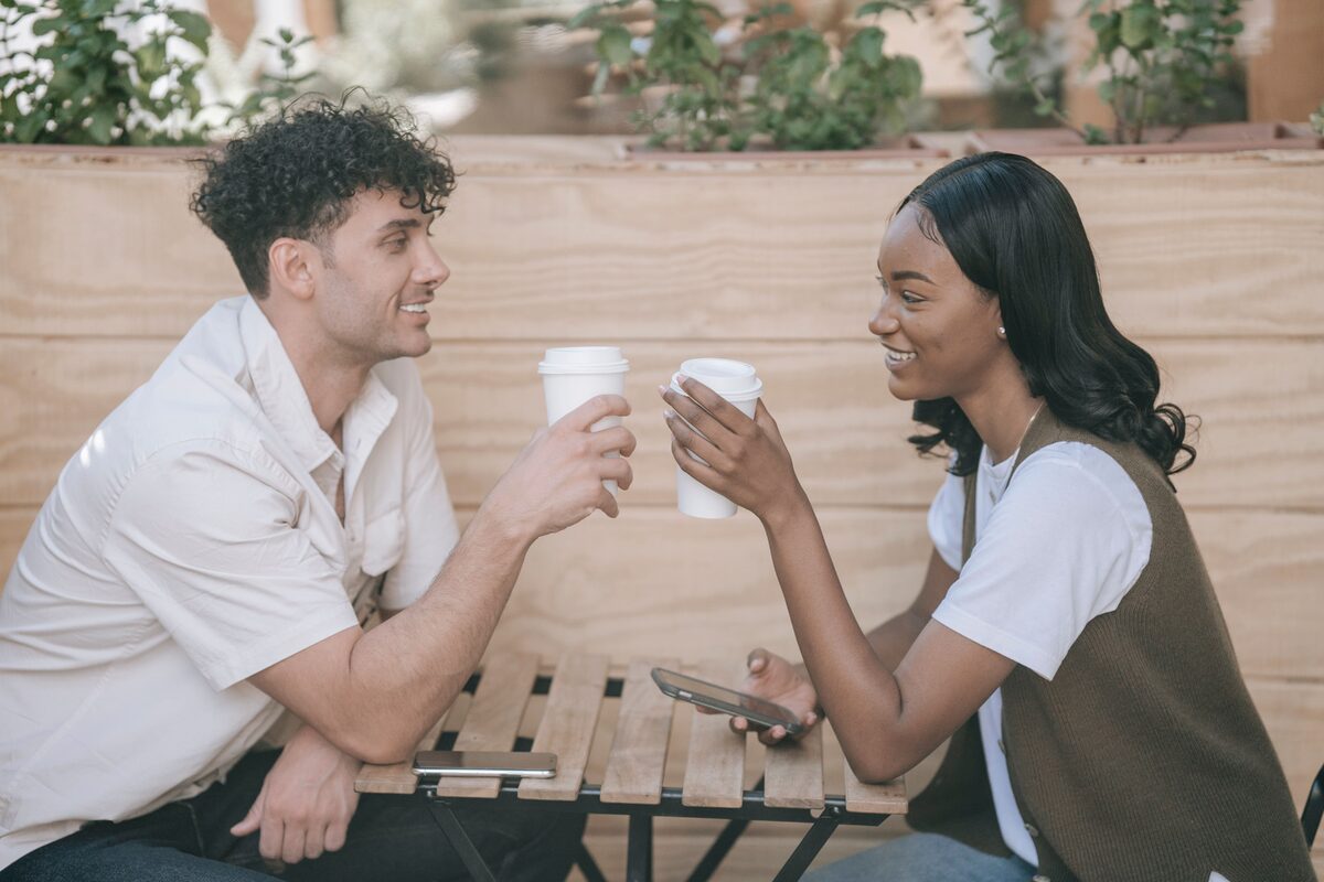 Two adults sharing a moment over coffee outdoors, showcasing connection and leisure.