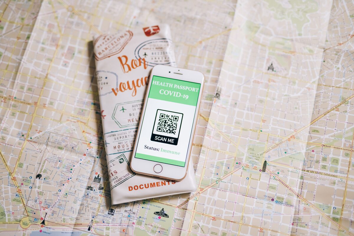 Top view of a smartphone with COVID-19 health passport and travel documents on a map.