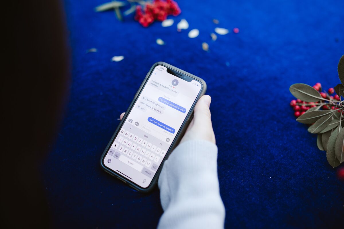 A hand holding a phone with a messaging thread open